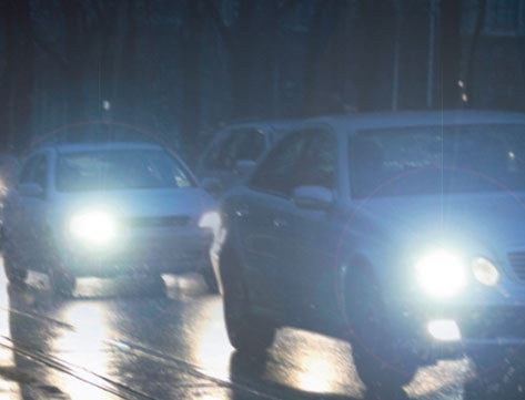 At night, what should you do if an oncoming vehicle's headlights dazzle you?