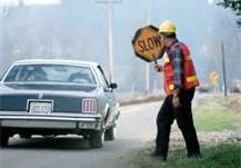 You see a signal person at a road construction site ahead. You should obey his or her instructions:
