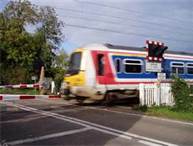 If you are driving towards a level crossing, what would be the first indicator of an approaching train?