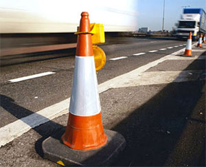 What must you do if you see orange construction signs and cones on a freeway?