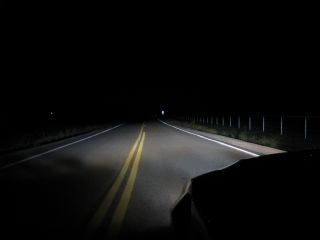 You must use your low headlight beams at night when you are: