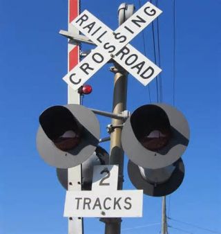 You arrive at a railroad crossing. The crossing has flashing red lights and a signal bell. You can see that a train is approaching. Which of the following is true?
