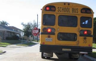 On a road not divided by a barrier or a median, when you come to a school bus that is stopped to load or unload children, you must: