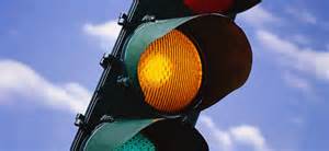 If you approach an intersection with a yellow light, you must: