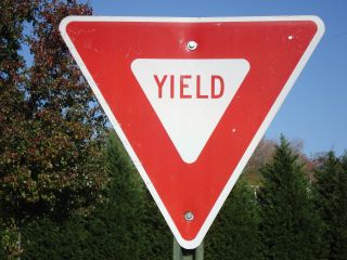 A yield sign indicates that a driver must slow down when approaching an intersection and _________ if a vehicle or pedestrian with the right-of-way is approaching from another direction.