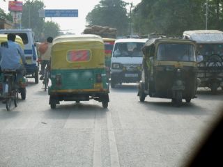 In traffic moving two lanes in each direction, the car directly ahead of you is waiting to make a right turn. You may: