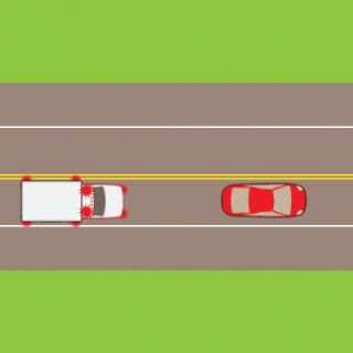 In Texas, you spot an emergency vehicle approach with its flashing lights switched on. What should you do?